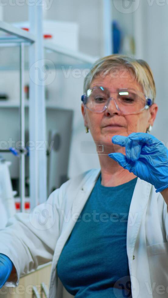 Woman lab technician looking at virus sample in modern equipped laboratory. Senior scientist working with various bacteria tissue and blood tests, concept of pharmaceutical research for antibiotics photo