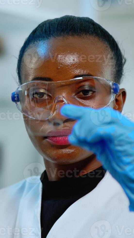 Close up of african chemist looking at virus test in equipped lab. African scientist working with various bacteria, tissue and blood samples, concept of pharmaceutical research for antibiotics. photo