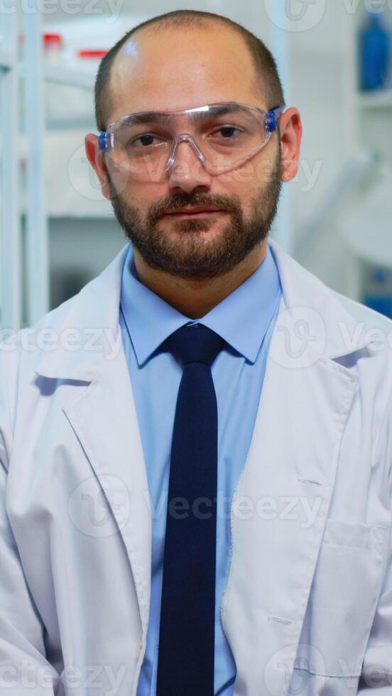 Tired doctor looking exhausted at camera in modern equipped lab. Multiethnic team examining virus evolution using high tech and chemistry tools for scientific research, vaccine development. photo
