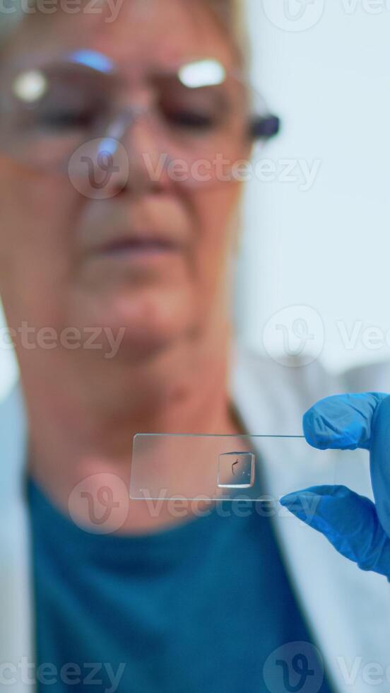 Elderly scientist checking virus evolution looking at samples in modern equipped laboratory. Senior doctor working with various bacteria tissue and blood tests, pharmaceutical research for antibiotics photo
