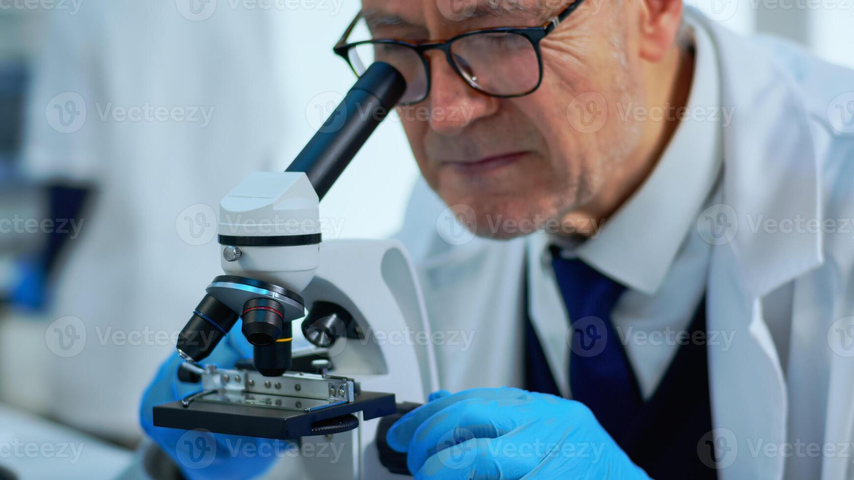 Elderly man in modern equipped lab making research using microscope. Senior scientist working with various bacteria tissue, blood samples, concept of pharmaceutical research for antibiotics photo
