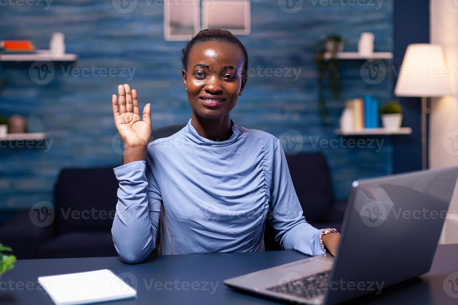 Dark skinned freelancer woman waving at camera in the course of conference Black freelancer working with remotely team chatting virtual online conference. photo