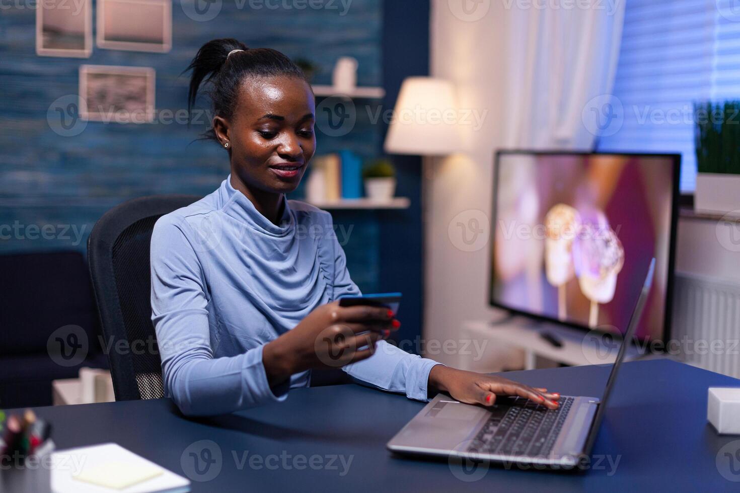 African woman looking at cw security code typing data on webstite for web store. Employee making paymant transaction from home on digital notebook. photo