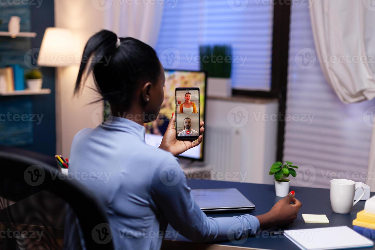 African business consultant talking with clients late at night from home office Busy employee using modern technology network wireless doing overtime for job. photo