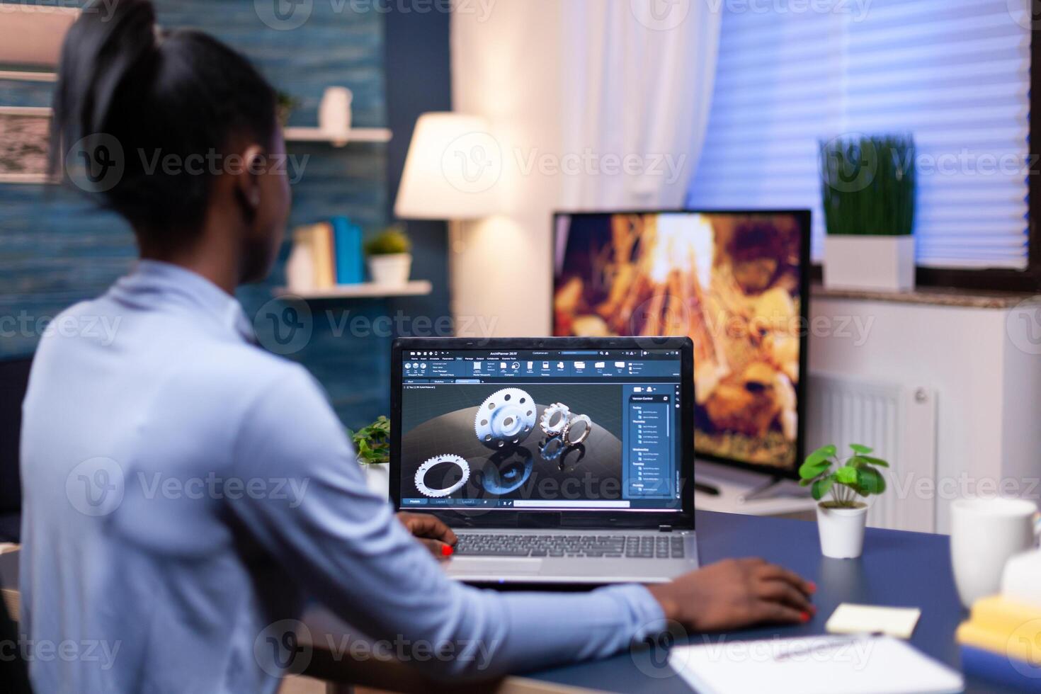 African freelancer using cad to design a technical concept from home office in the evening. Industrial black female engineer studying prototype idea on personal computer showing software on device display photo