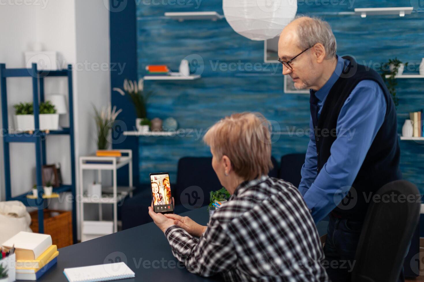 Senior couple talking with relatives during call. Happy grandparent communicating with family via online web internet conference using modern internet technology while sitting in the living room photo