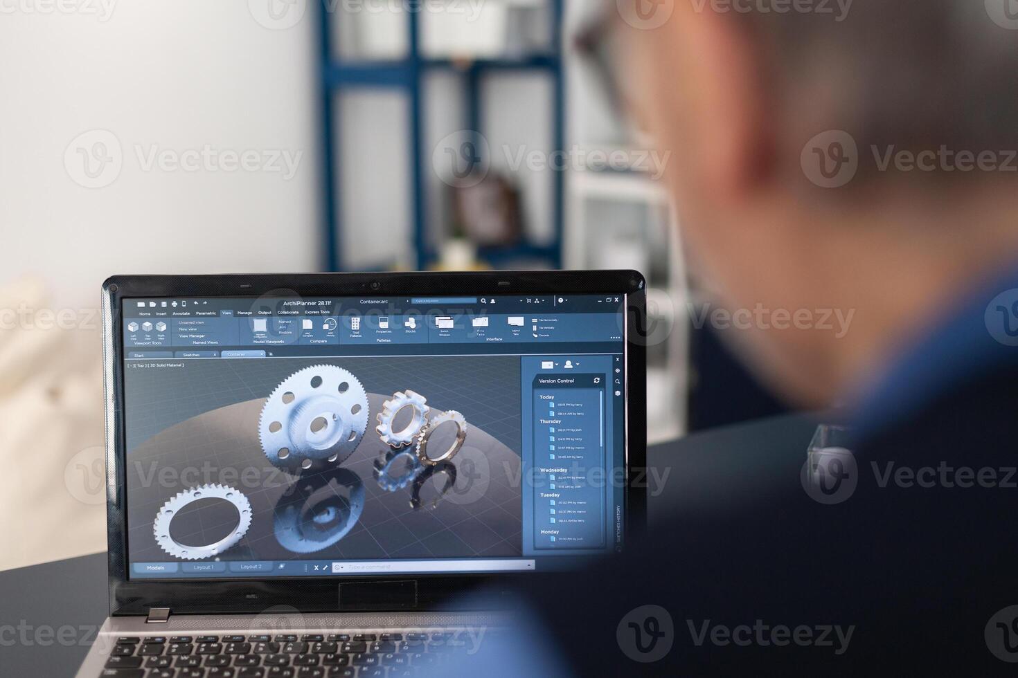 Engineer designed gears parts using professional software. Experienced engineer working from home office on mechanical project using laptop computer technology and wife is reading a book on sofa. photo