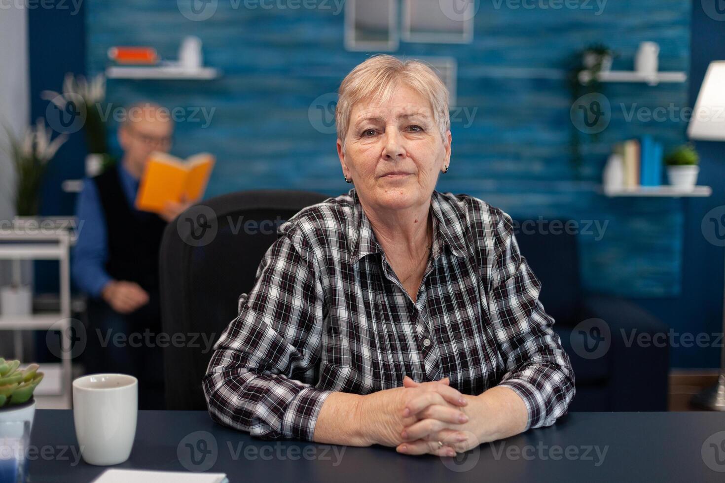 Portrait of senior woman looking at camera while enjoying a mug of coffee. Healthy happy elderly woman in home living room enjoying her retirement photo