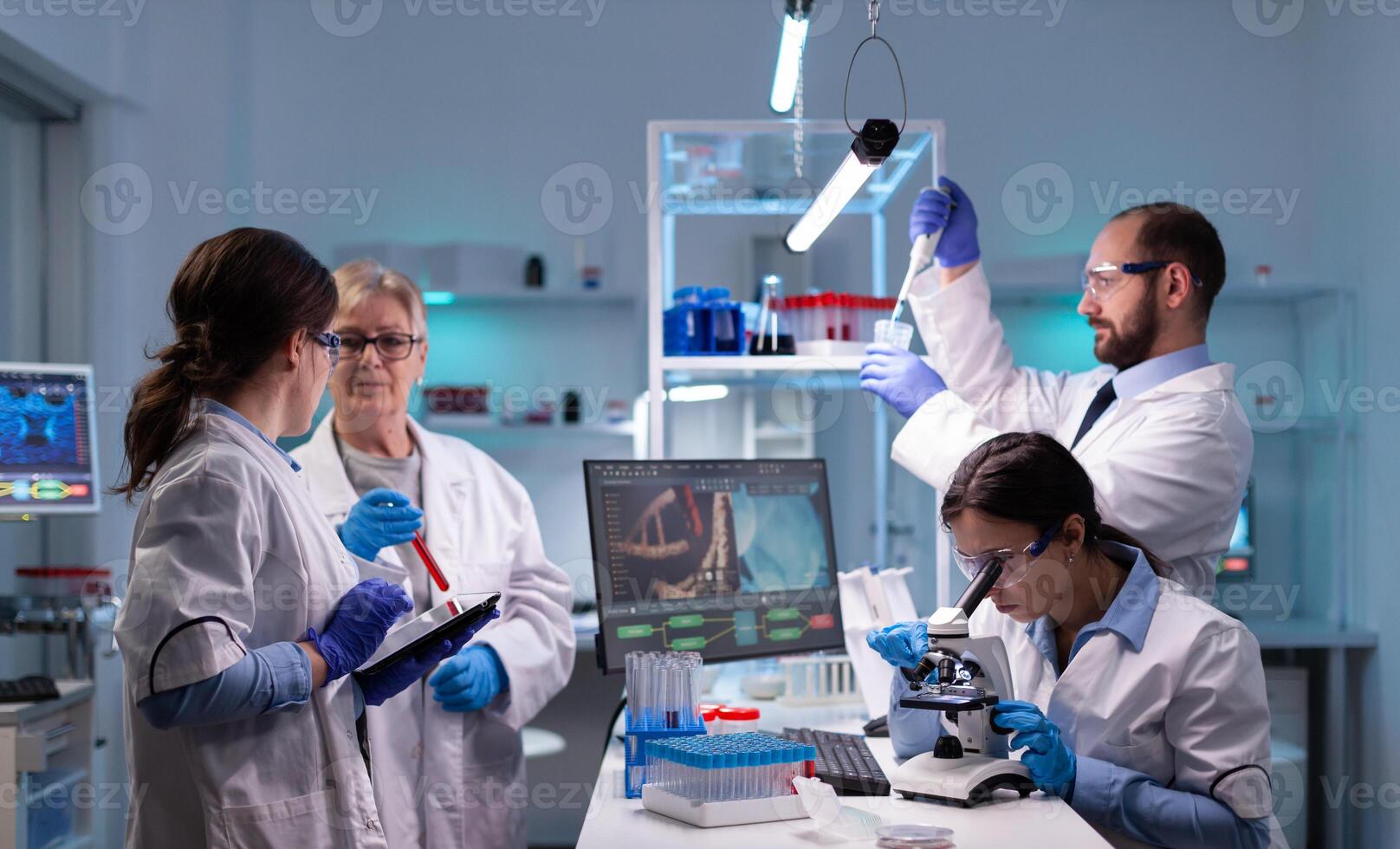 Team of scientific investigators conducting experiments in lab using microscope and micropipette. Laboratory for disease research with professional equipment for virus study and diagnosis development photo
