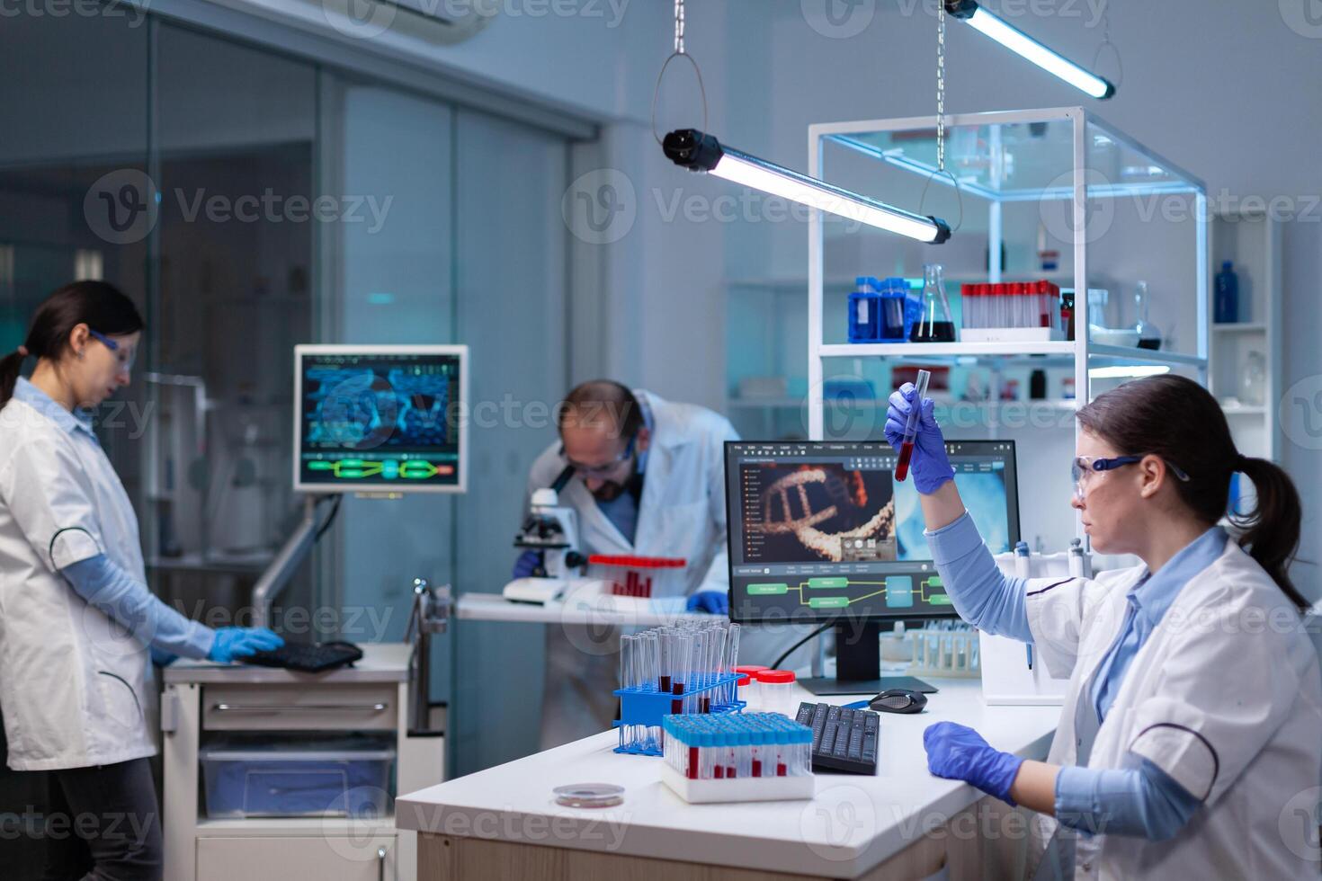 Team of scientific researchers working with professional modern equipment in laboratory. Chemists in pharmaceutical lab examining sample for medical experiment with technology for medicine industry. photo