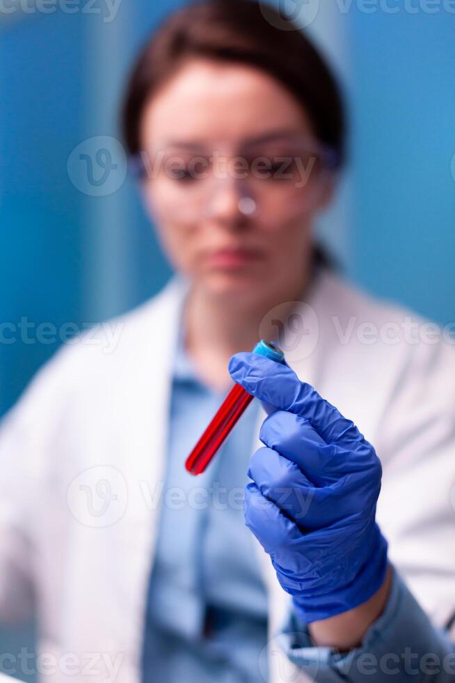 Close up of sample of with blood hold by scientist doctor in hospital. Researcher in chemical medicine lab working with professional technology equipment for healthcare development. photo