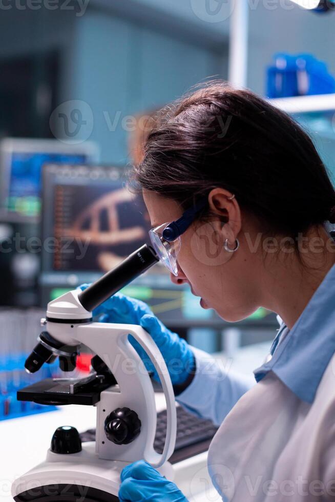 Scientist examining researching analyzing virus loking through microscope. Research chemists working in lab with high tech analyzing blood and genetic material samples discovery, photo