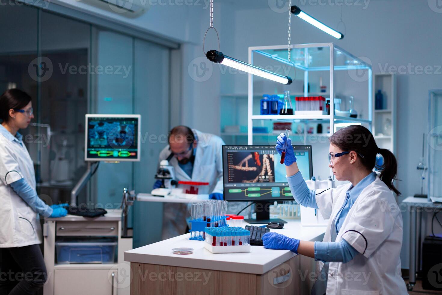 Team of scientific researchers working with professional modern equipment in laboratory. Chemists in pharmaceutical lab examining sample for medical experiment with technology for medicine industry. photo