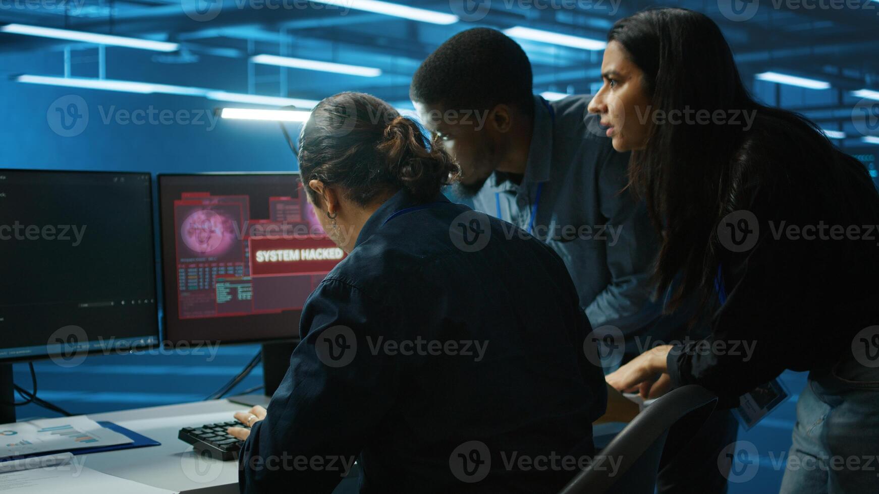 Multiethnic programmer team in server farm workspace surprised by data threatened by hacking attack on computers. Diverse colleagues scrambling to protect data center from unauthorized access photo