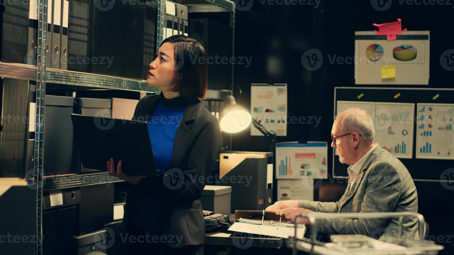Private investigator organizes archived files for easy access, searching for old file cases to cross reference data. Law enforcement agent looking for classified folders in archive room. Camera A. photo
