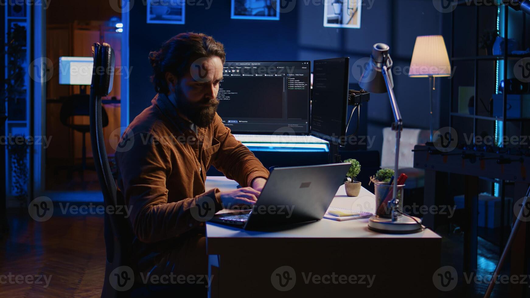 Computer scientist putting headphones on while developing code on PC, making time pass faster during remote job shift. IT admin doing multitasking in home office while listening music, camera B photo