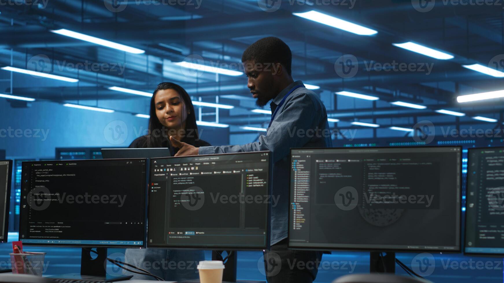 Multiethnic team of engineers uses laptop to do programming for servers providing computing resources for different workloads. Diverse colleagues using notebook to supervise data center supercomputers photo