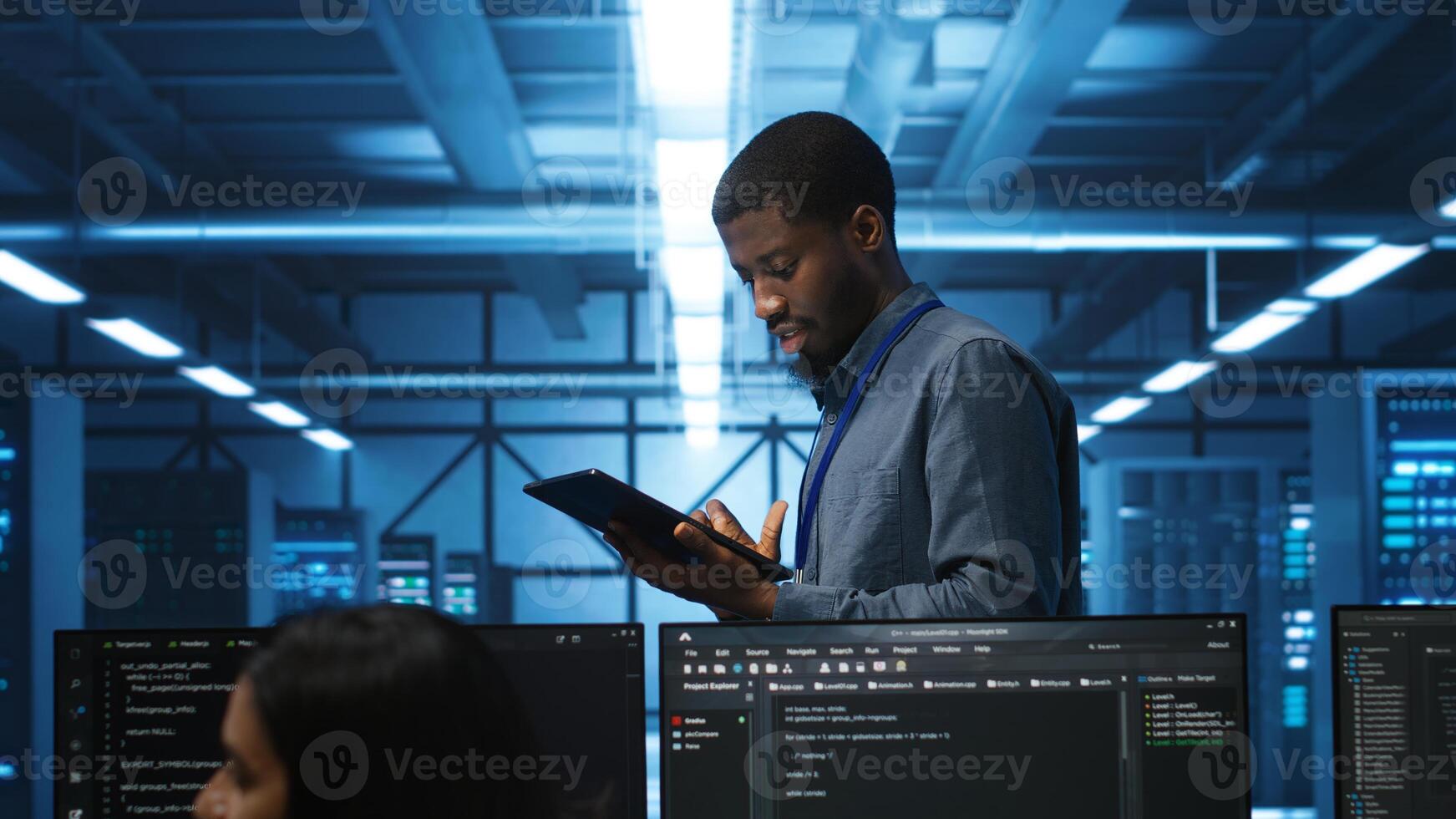 Engineer inputting data on tablet in server hub, monitoring data center energy consumption across hardware. Technician inspecting mainframes, ensuring malfunctions are repaired photo