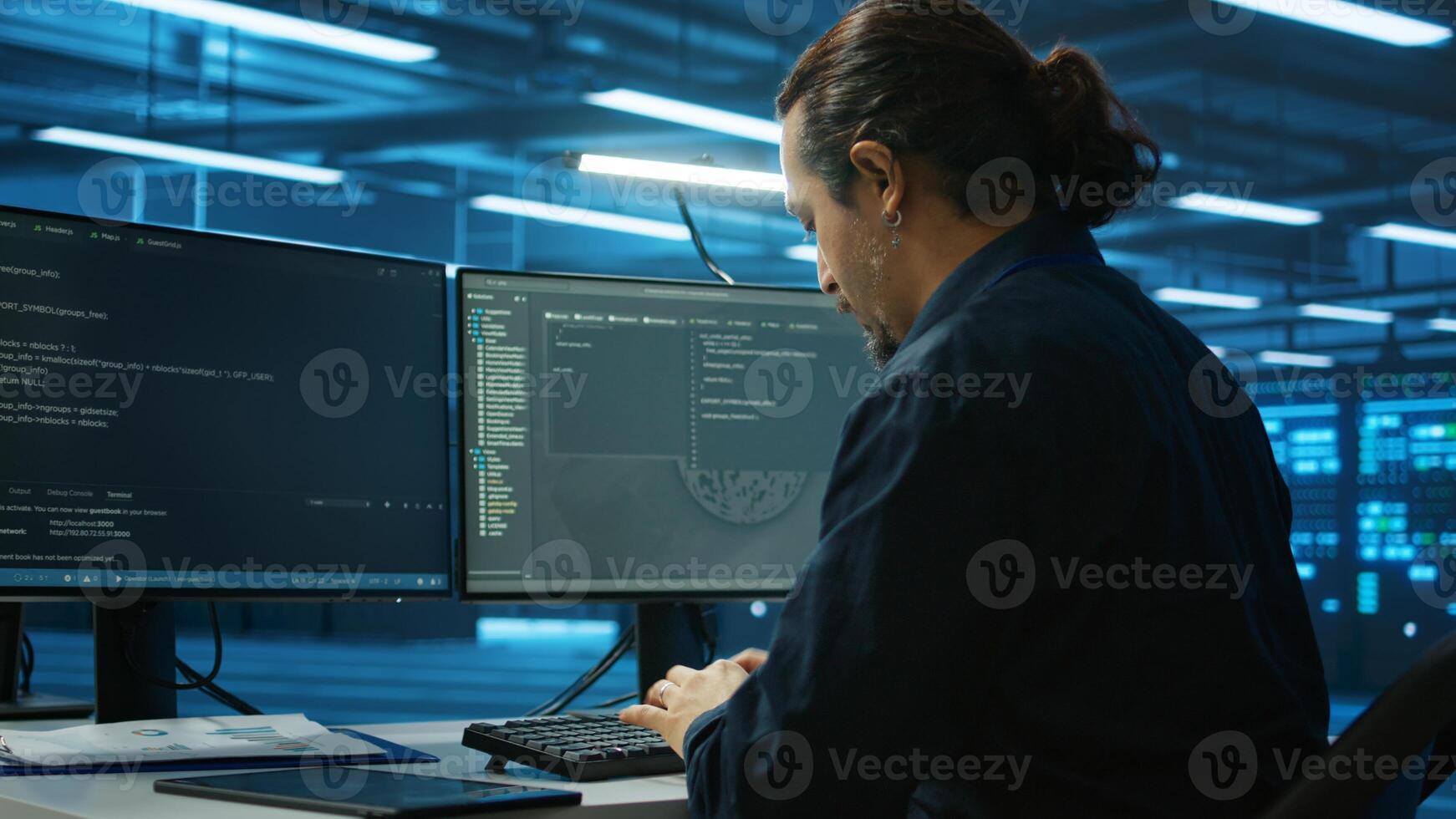 System admin focused on programming in server room housing advanced equipment storing massive datasets. Developer typing code on PC to mend data center racks doing complex computational operations photo