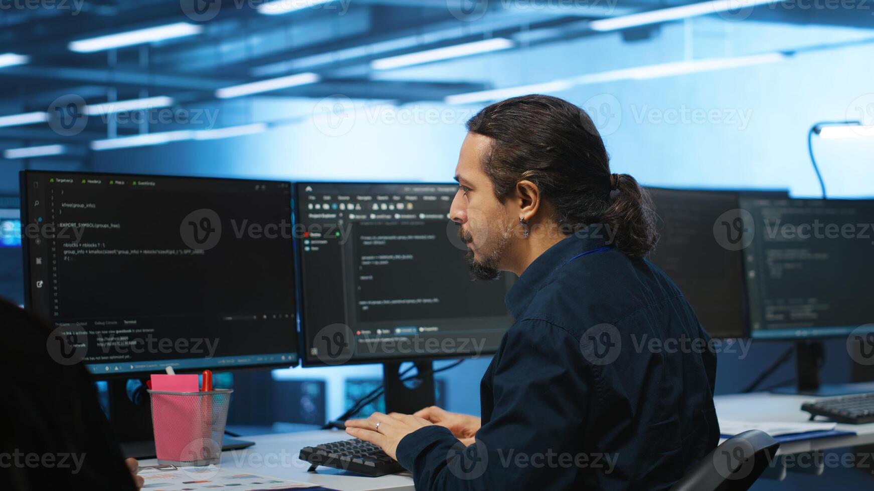 Knowledgeable engineer upgrading equipment in data center, zoom in shot. Specialist at PC desk in high tech establishment overseeing server rows, typing on keyboard, close up shot photo