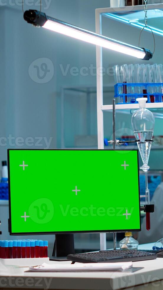 Team of scientists working in background of modern laboratory using computer with green screen, mockup display, chroma key monitor, analysing experiment evolution, high tech development lab. photo