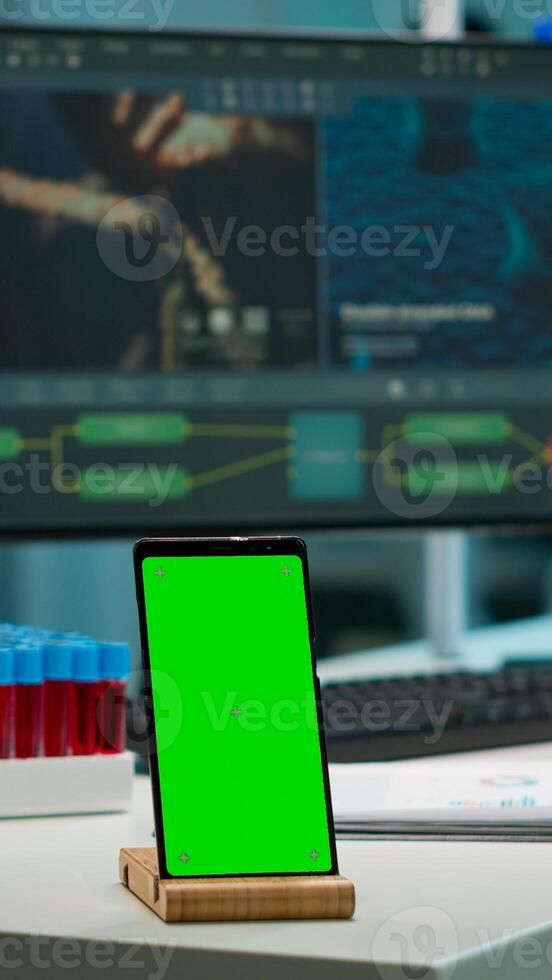 Smartphone with green screen working in laboratory with mock up, chroma key display while professional engineer testing virus evolution in background. High tech development lab with blood samples photo