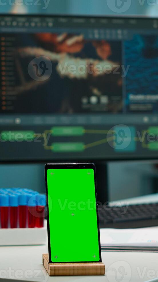 Display phone with green screen, mock up on template placed on desk in scientific lab while team of medical researcher scientists analysing virus evolution at digital monitor conducting experiment photo