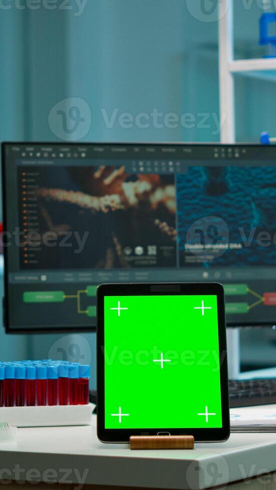 Team of scientists working in background of modern laboratory using tablet with green screen, mockup display, isolated chroma key monitor, analysing experiment evolution, high tech development lab. photo