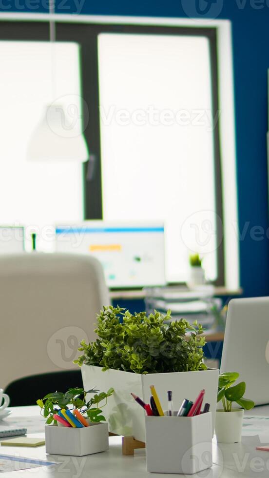 Brainstorm area in business center with nobody in it, shot of empty room with modern furniture, white shelves and blue wall. Modern business meeting zone interior with conference table and white chair photo
