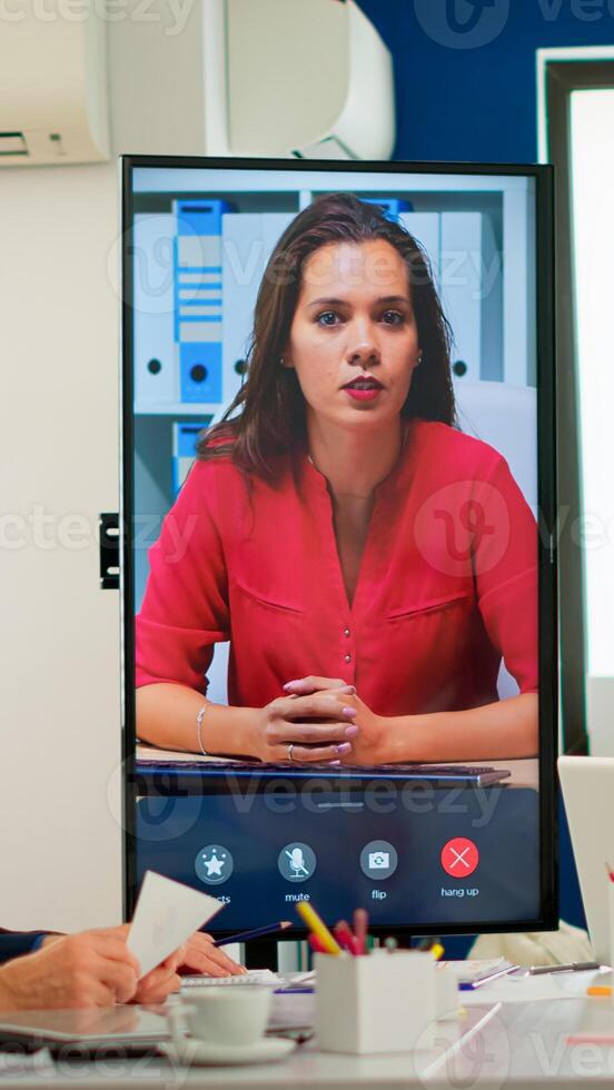Diverse executive team meeting at conference call looking at huge display. Business people talking to webcam, do online conference participate internet brainstorming, distance office discussion photo