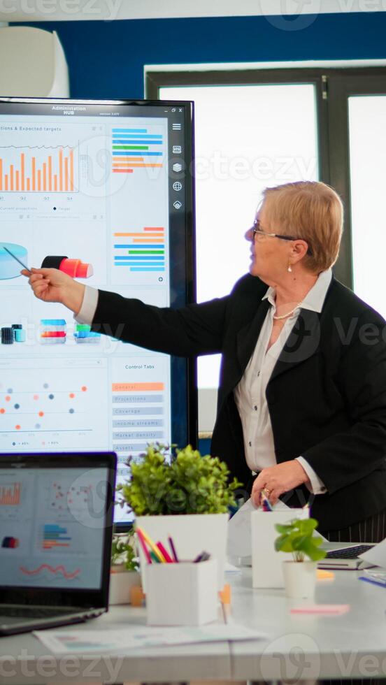 Experienced senior woman CEO CTO of start up company sharing financial reports project strategy briefing diverse group of investors. Multiethnical businesspeople working in professional startup financial company during conference photo