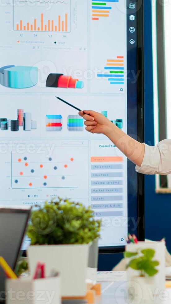 Young businesswoman coach leader conference speaker giving business presentation explain project strategy pointing on digital board training diverse team group at office boardroom seminar meeting photo