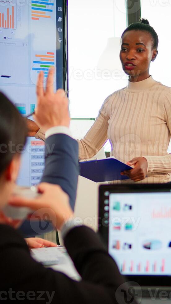 African entrepreneur making project presentation during brainstorming, planning strategy of company. Multiethnical businesspeople working in professional startup financial office during conference photo