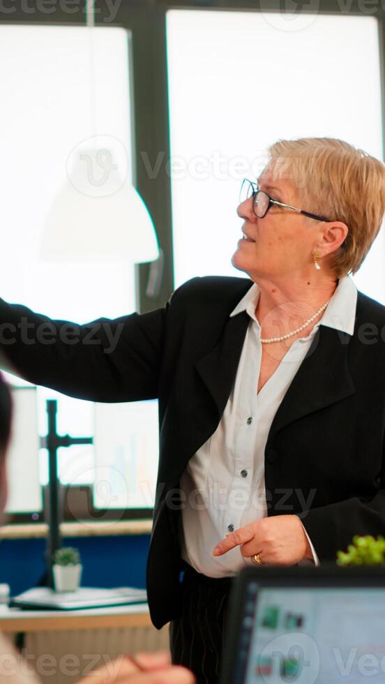 Serious senior manager executive and diverse team people analyzing digital project presentation briefing, sharing ideas in teamwork, discussing financial plan in office corporate meeting room photo