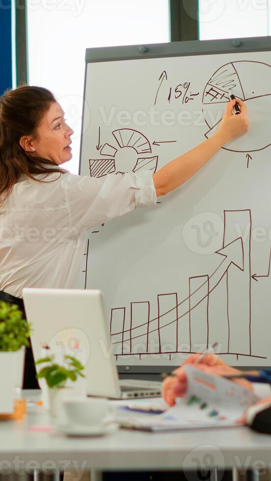 Focused team leader presenting marketing plan to interested multiracial coworkers. Serious speaker boss executive, business trainer explaining development strategy to motivated mixed race employees. photo