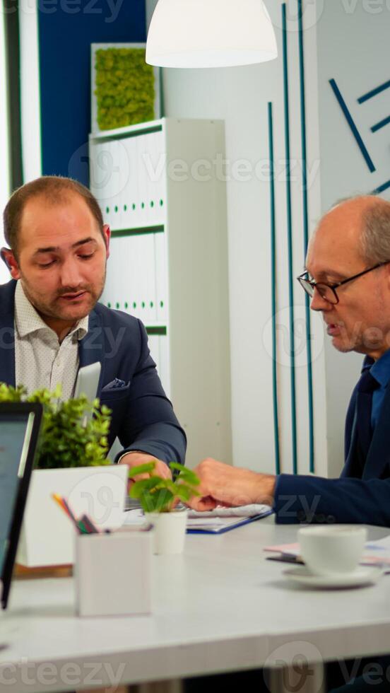 Businessman in suit talking to diverse business people partners sitting at conference table. Project leader discussing with teamworkers in meeting broadroom, group negotiations speaking with clients photo