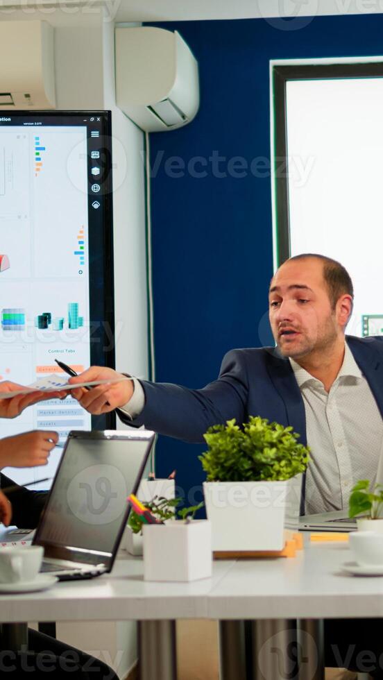 Diverse businesspeople discussing company strategy, project manager giving tasks to employee. Company leader talking with teamworkers in meeting broadroom, group negotiations speaking with clients photo