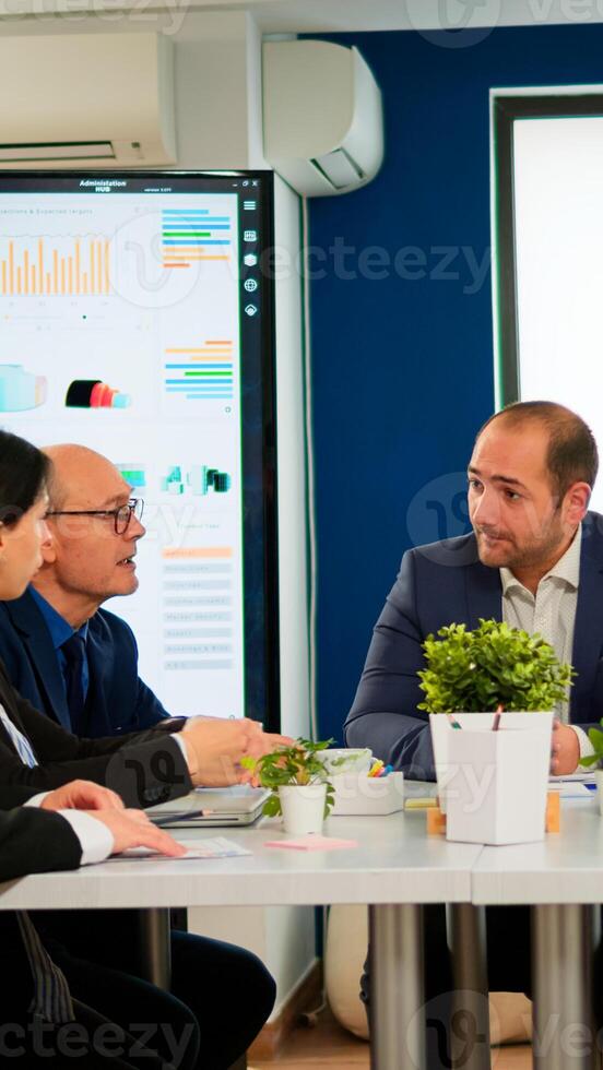 Young man company leader waiting diverse team for business conference meeting sitting in broadroom at table. Executive director briefing multiethnical people, explaining start up financial reports photo
