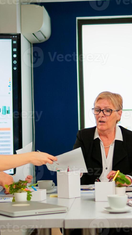 Start up team meeting with company leader planning financial strategy, analysing reports sharing paperwork. Colleagues working in office at conference table in startup management company photo