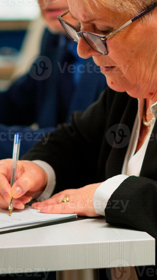 Busiess partners discussing new project for company evolution, senior manager woman checking tasks on clipboard and signing new contract. Executive director meeting shareholders in start up office photo