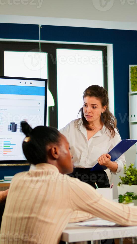 Diverse employees team with young woman leader working together in modern boardroom, manager executive pointing at digital interactive whiteboard, discussing project statistics, sharing ideas photo