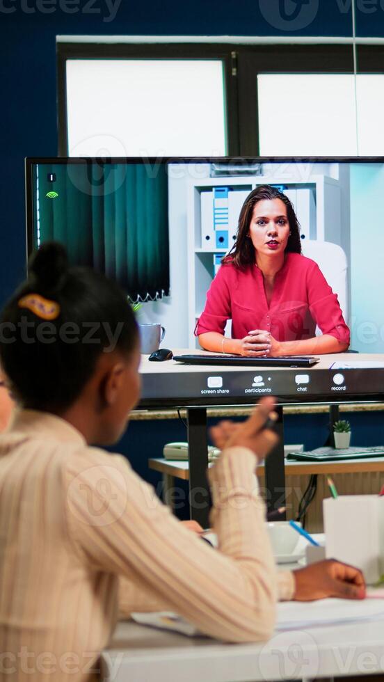 Executive manager discussing with remote colleagues on call sitting in business office, briefing remote team. Diverse team planning strategy during conference, online brainstorming photo