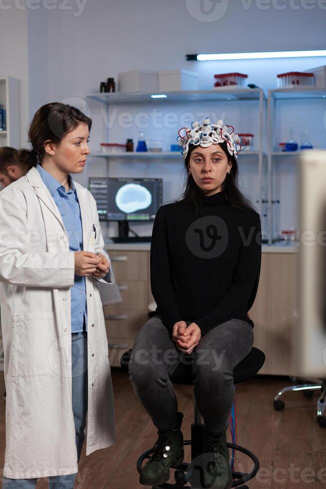 Neurologist doctor showing tomography expertise to woman patient with eeg scanner during neurology experiment in lab, Specialist doctor analyzing brain evolution monitoring nervous system activity photo