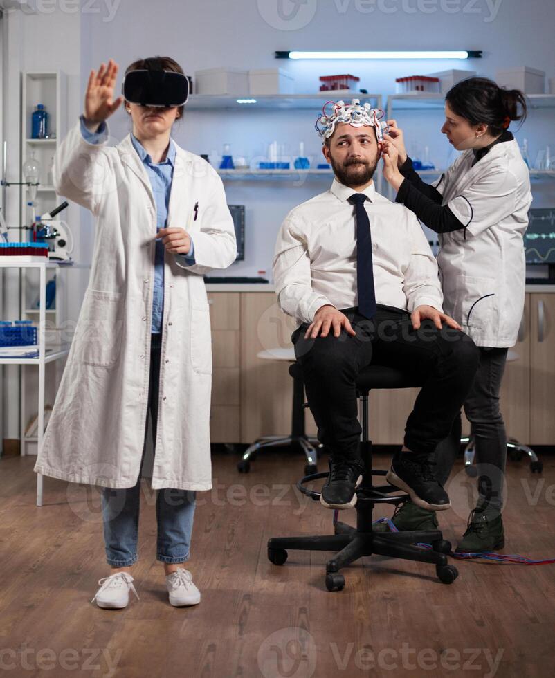 Researcher woman wearing virtual reality headset during neurology experiment in medical laboratory. Neurologist doctor adujusting eeg scanner monitoring brain activity analyzing nervous system photo