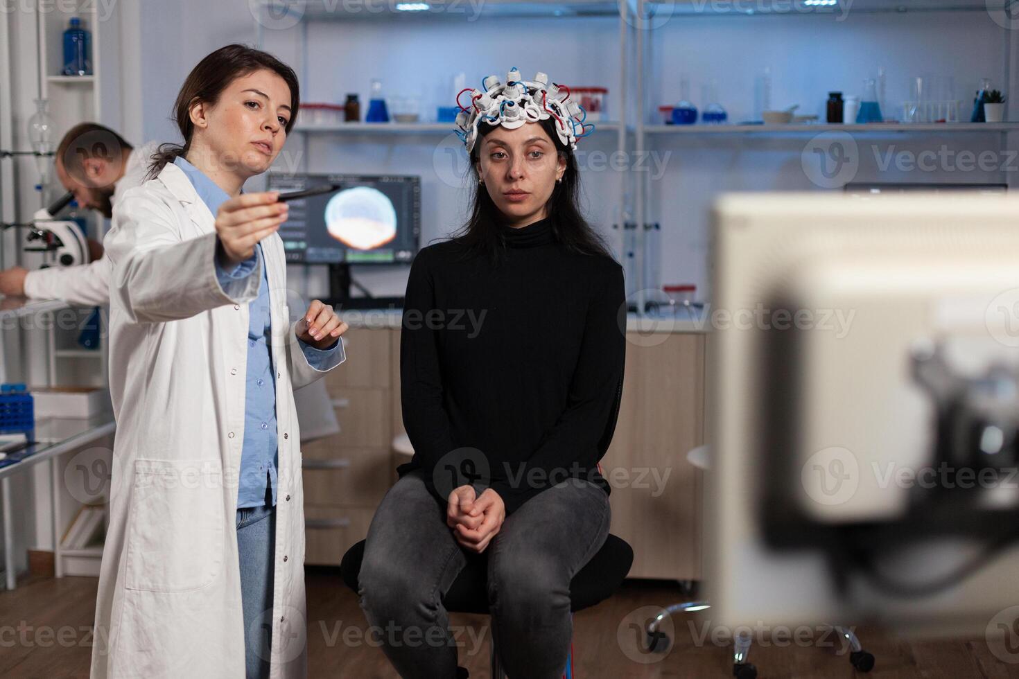 Physician neurologist doctor analyzing brain evolution of patient with eeg scanner on head during neuroscience experiment in modern laboratory. Physician researcher monitoring nervous system activity photo