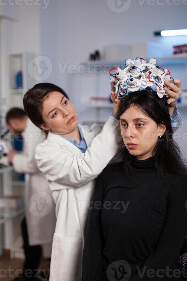 Researcher engineer woman putting eeg scanner on woman patient head during neurology experiment in medical laboratory. Neurologist doctor analyzing brain evolution monitoring nervous system activity photo