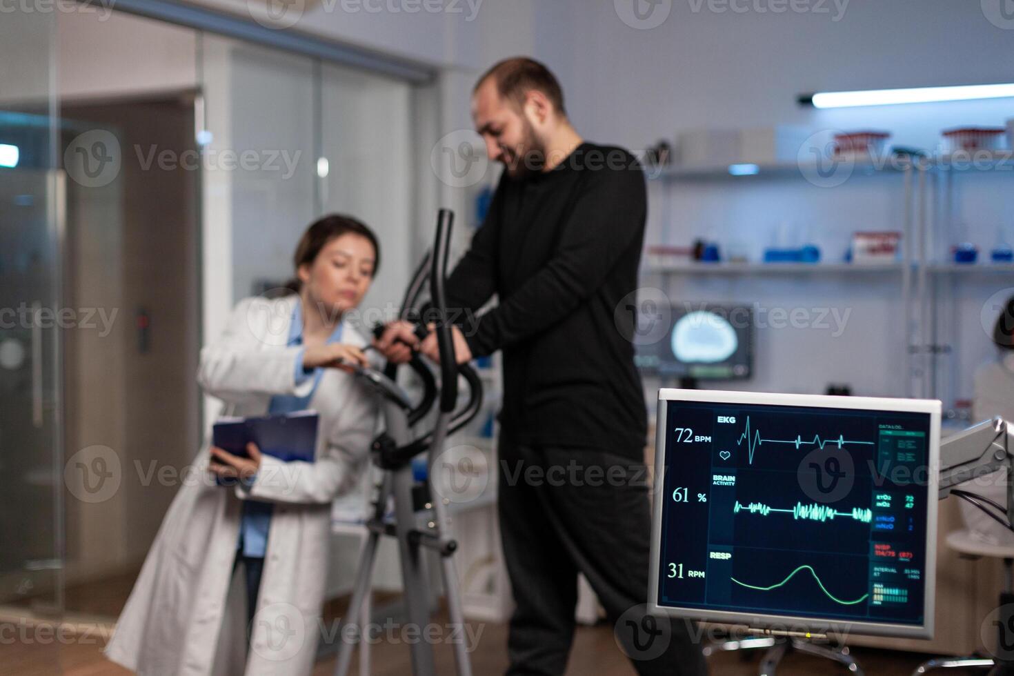 Specialist researcher doctor discussing with sportman in gym training equipment monitoring body endurance during medical workout in modern laboratory. Researcher doctor analyzing EKG data photo