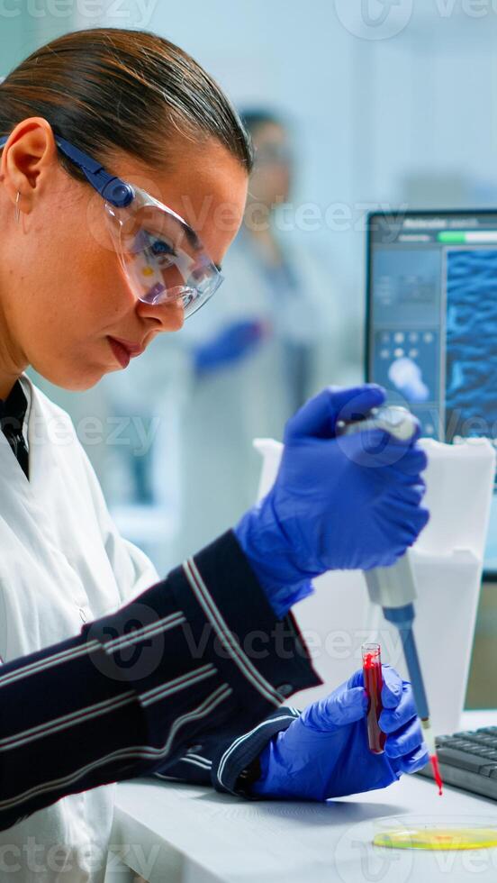 Research scientist using micropipette to extract blood sample on petri dish analysing chemical reaction sitting in laboratory. Doctor examining virus evolution using high tech and chemistry tools photo