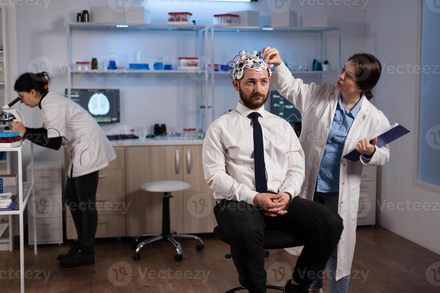 Researcher neurologist woman adjusting eeg headset monitoring brain activity of man patient during medical experiment in modern laboratory. Scientist doctor analyzing nervous system. Medicine service photo