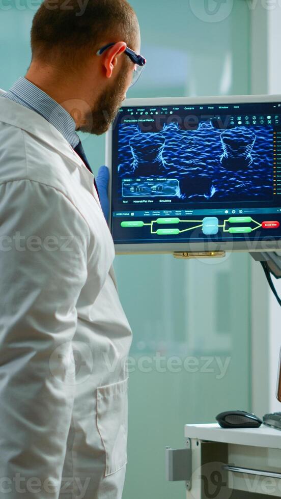 Scientist worried about virus evolution analysing DNA scan image standing in equipped laboratory typing at computer. Stuff examining vaccine development using high tech researching treatment photo